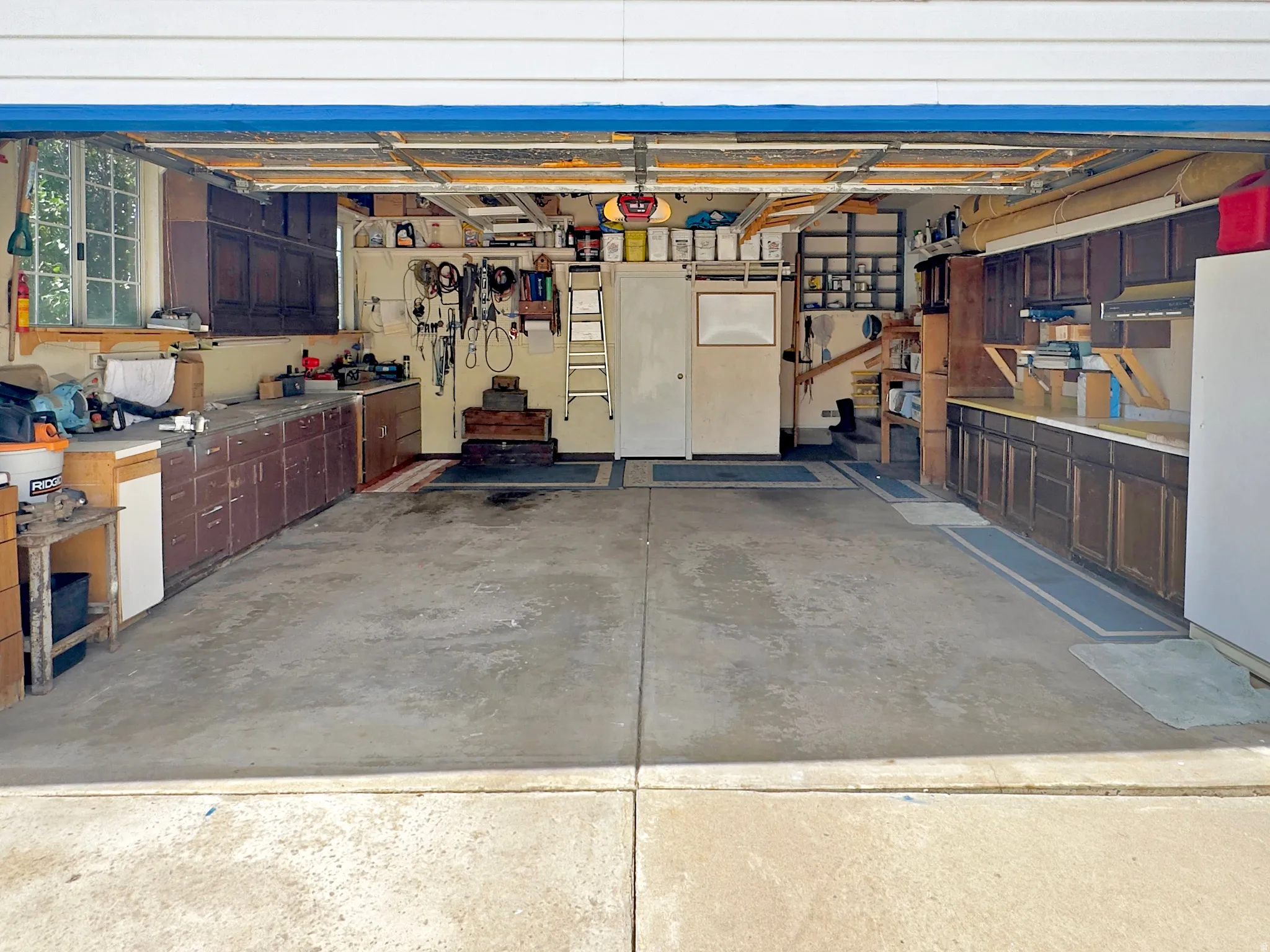 Spacious two-car garage featuring a concrete floor, built-in cabinetry, and a window for natural light