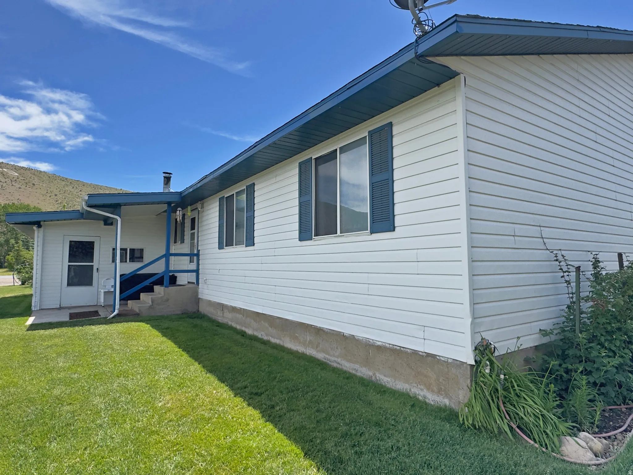 White siding exterior with blue trim and shutters, featuring a covered entry porch