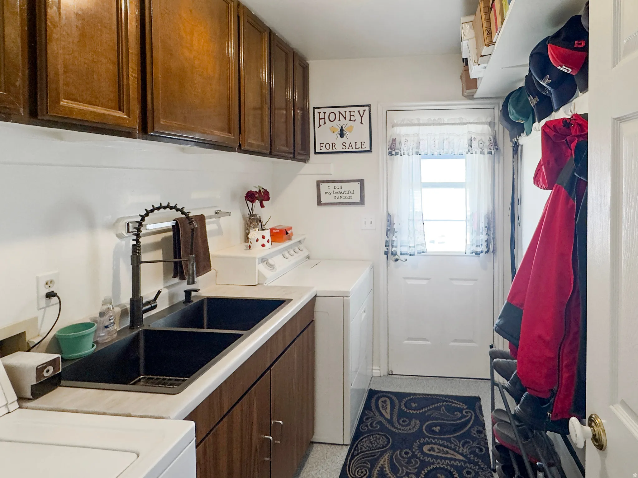Laundry area featuring a double basin sink with matte black faucet, wood-finish cabinetry, and a white countertop