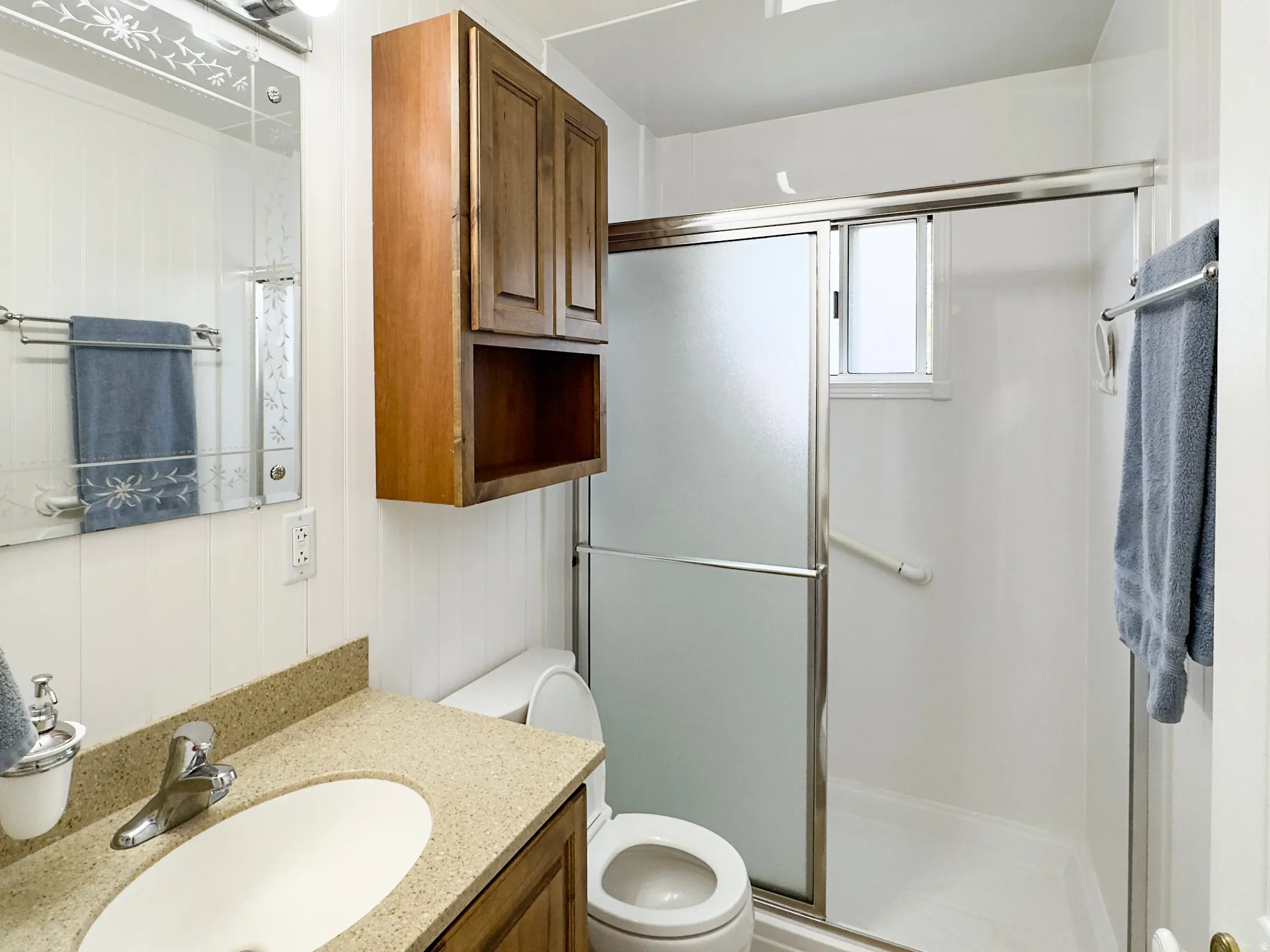 Bathroom featuring a shower with sliding frosted glass doors, a window, and a grab bar