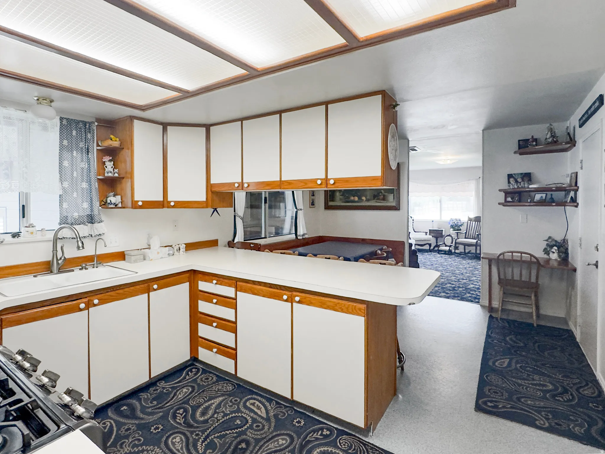 Kitchen featuring ample white cabinetry with wood-finish framing, white countertops, and a stainless steel sink with a gooseneck faucet