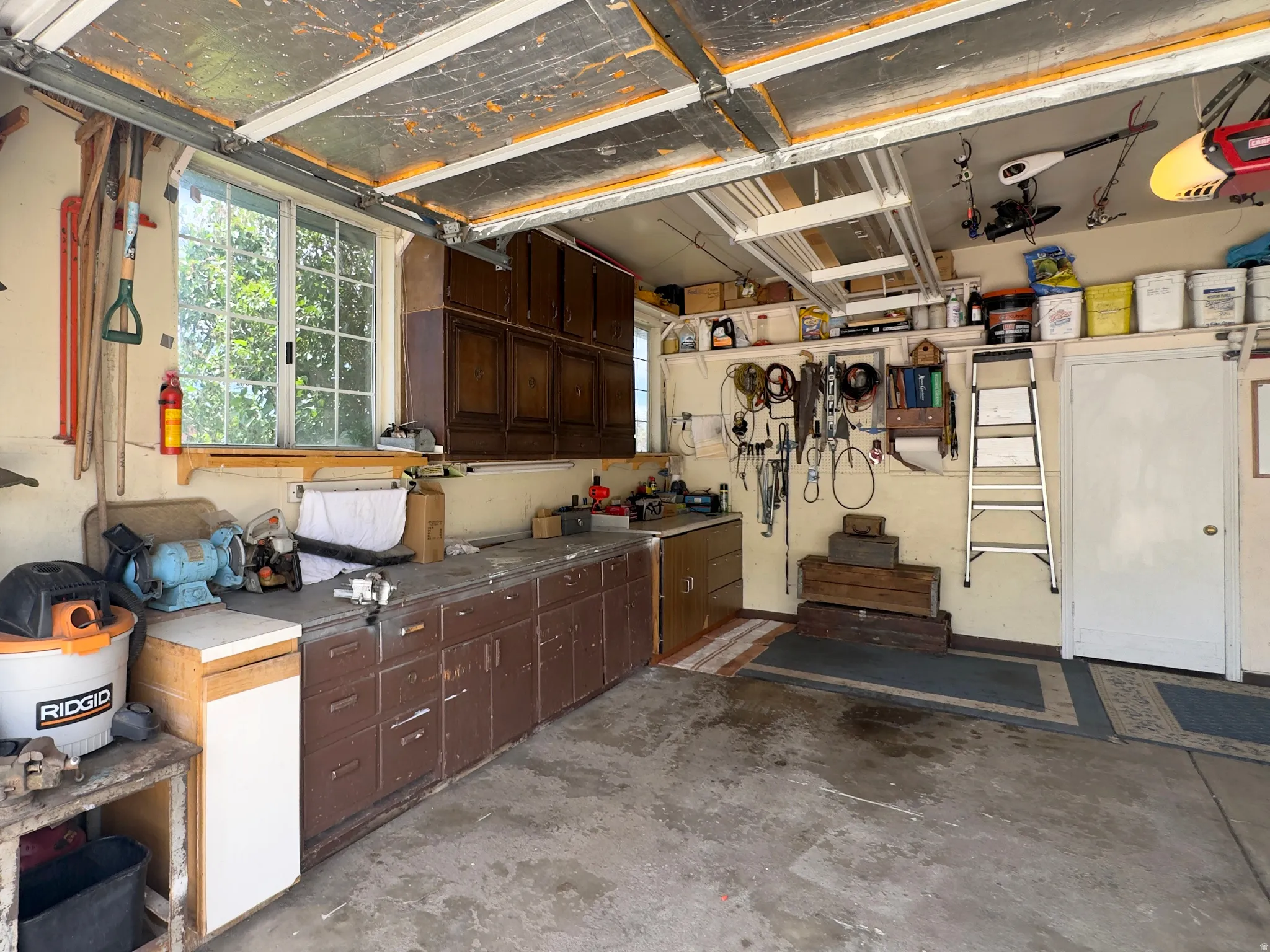 Attached garage featuring concrete flooring, a paneled window, built-in cabinetry, an integrated workbench, and a service door