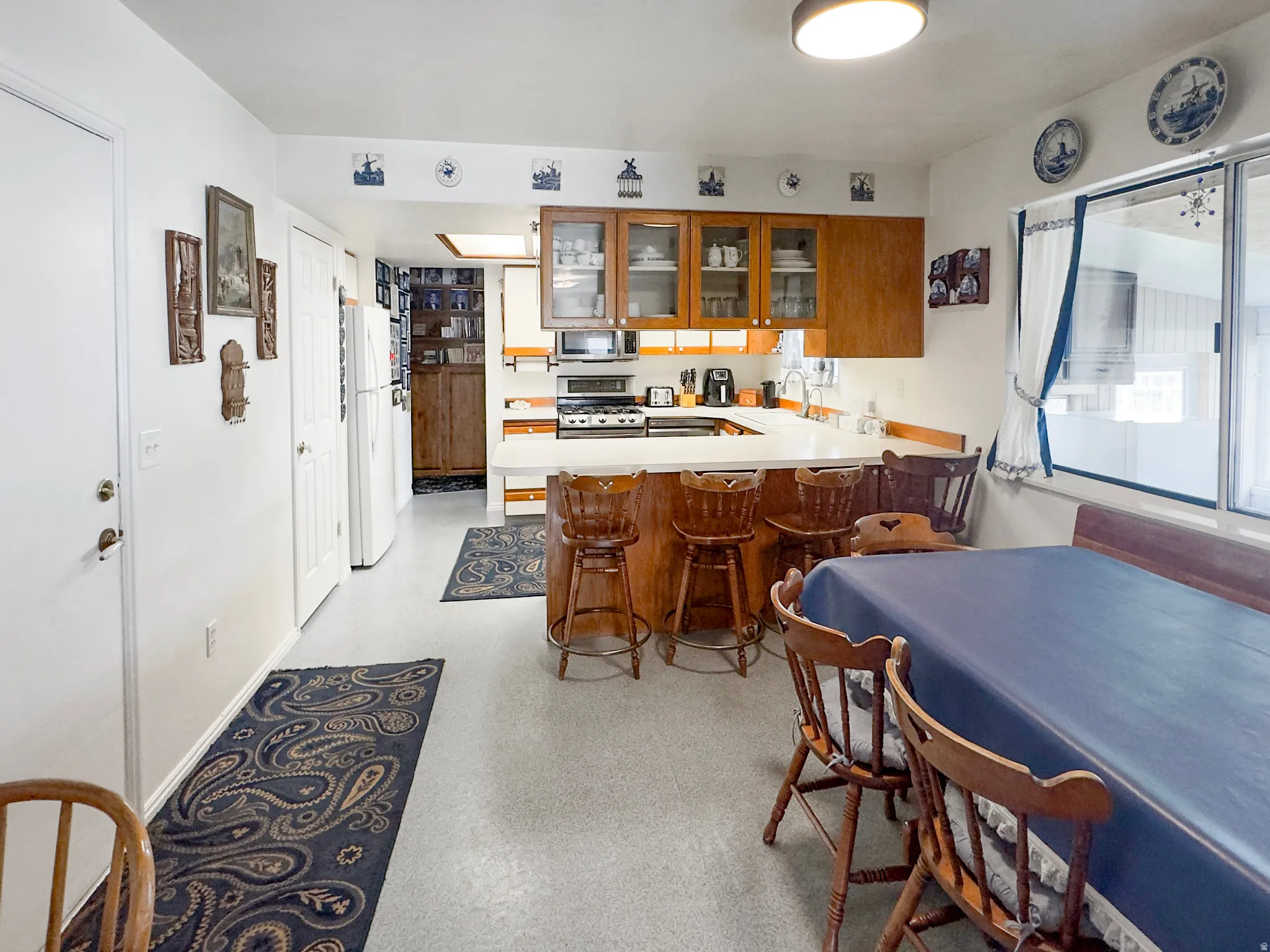 Kitchen featuring wood cabinetry, white countertops, built-in appliances, recessed lighting, and a breakfast bar with seating