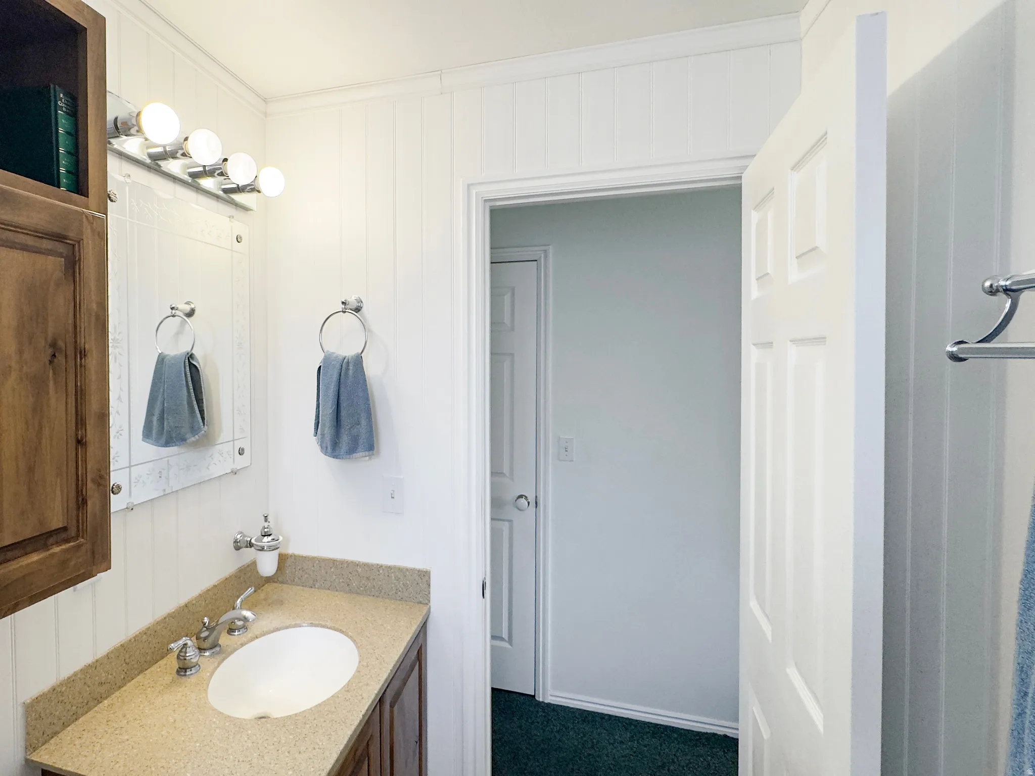Bathroom featuring a vanity with an oval undermount sink, a flecked countertop, and wood-finish cabinetry