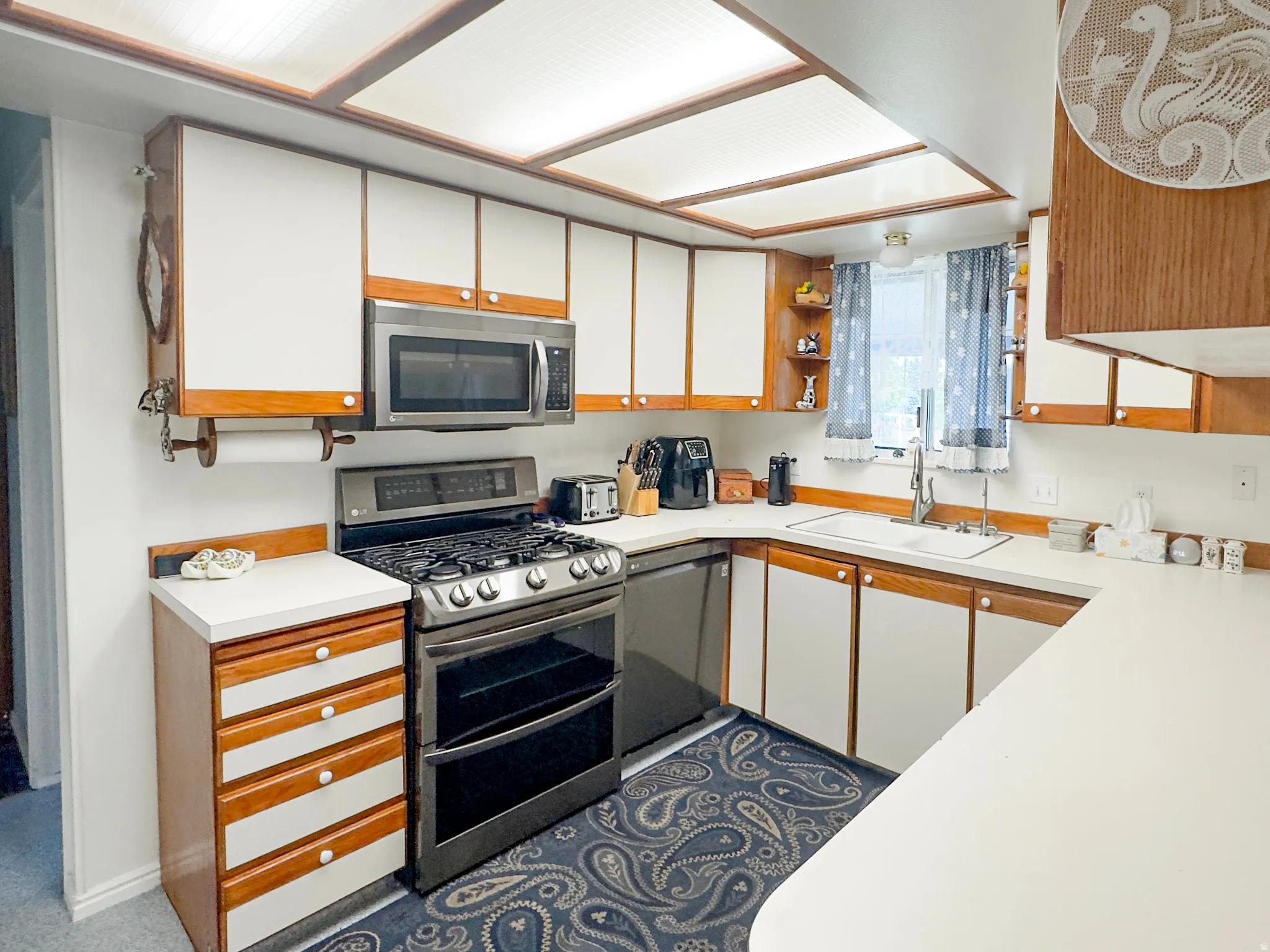 Well-appointed kitchen featuring a stainless steel gas range, coordinating microwave, and a double basin sink