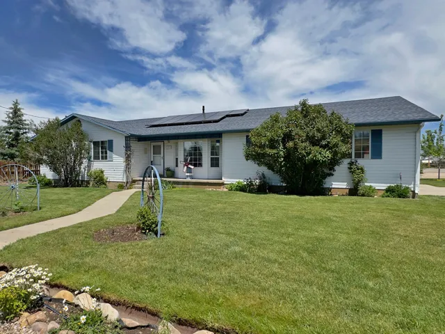 Single-story residence featuring white siding, a dark shingle roof with solar panels, and blue window shutters