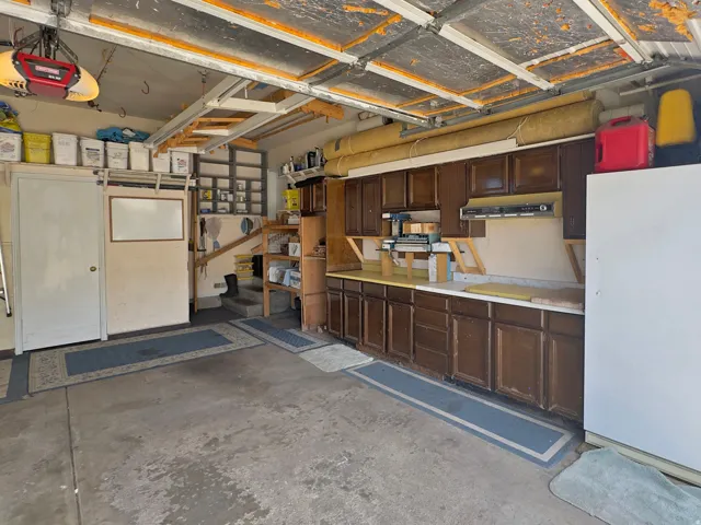 Garage space featuring concrete flooring, built-in cabinetry with dark wood-finish doors, and an integrated workbench surface