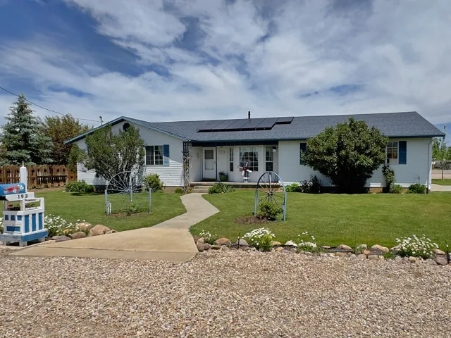 Single-story residence featuring white siding, a dark shingle roof with solar panels, and blue window shutters