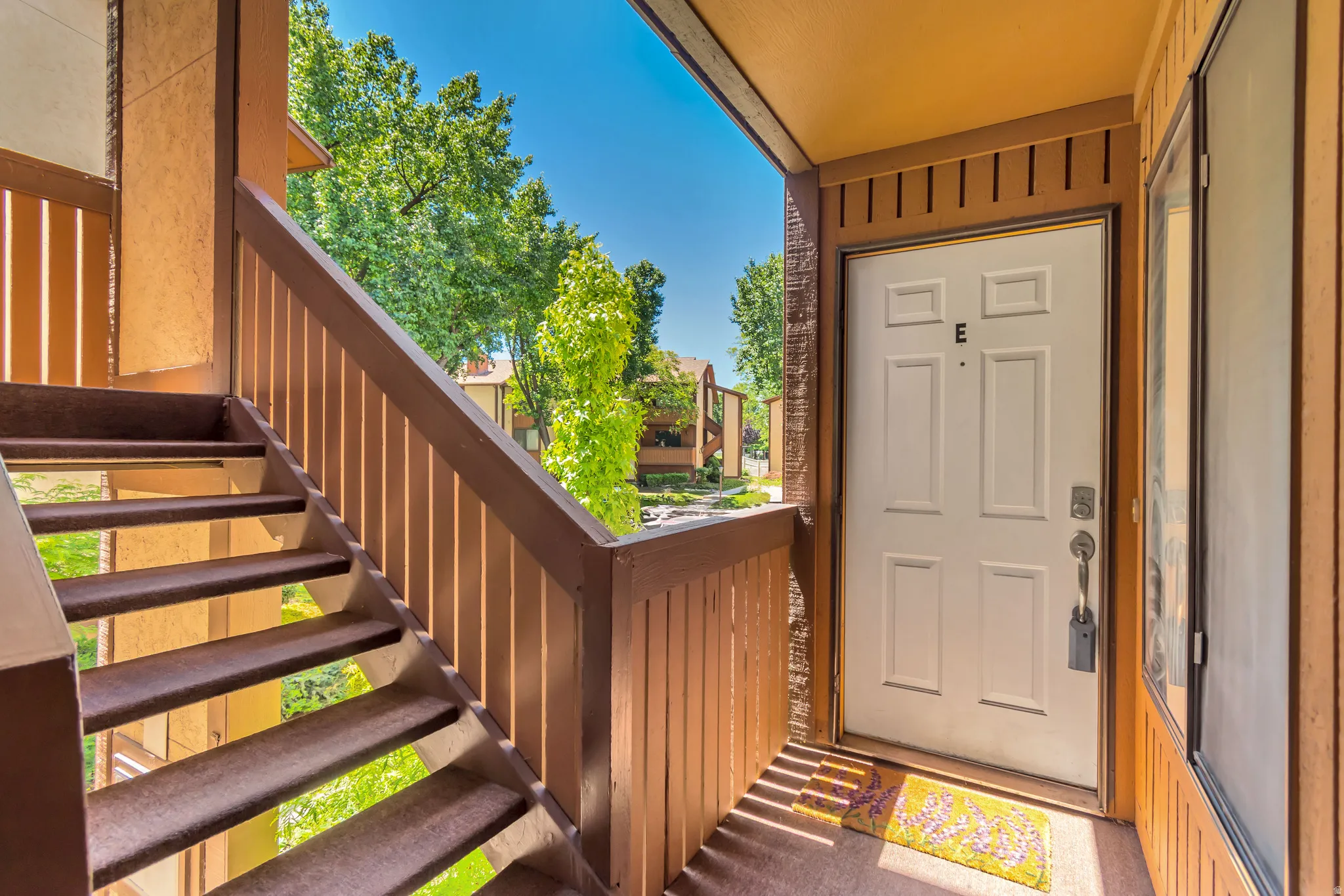 Entryway featuring a paneled door, wood-tone siding, and an outdoor carpeted staircase