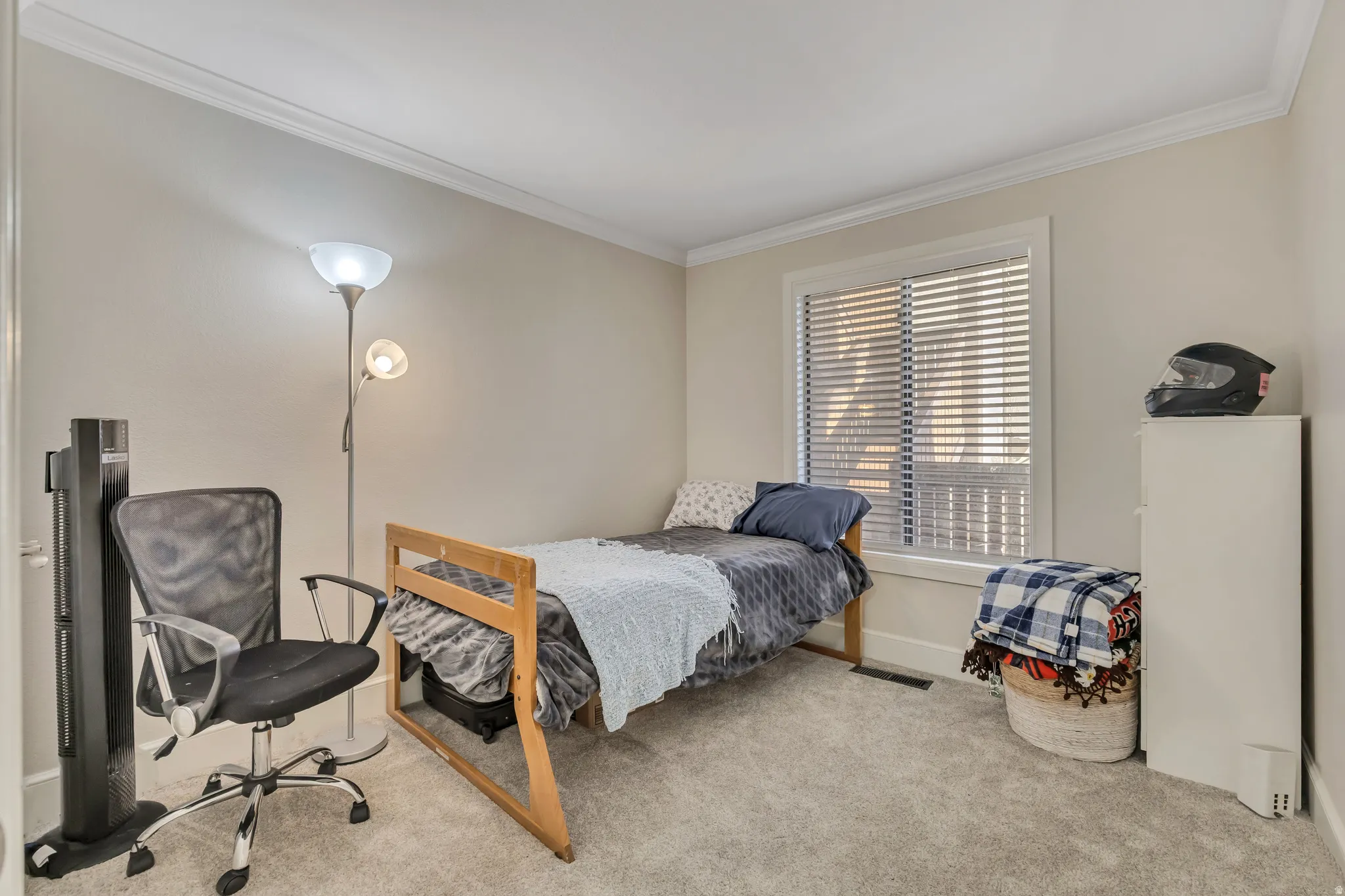 Carpeted room featuring a window with horizontal blinds, crown molding, white trim, and light neutral wall paint