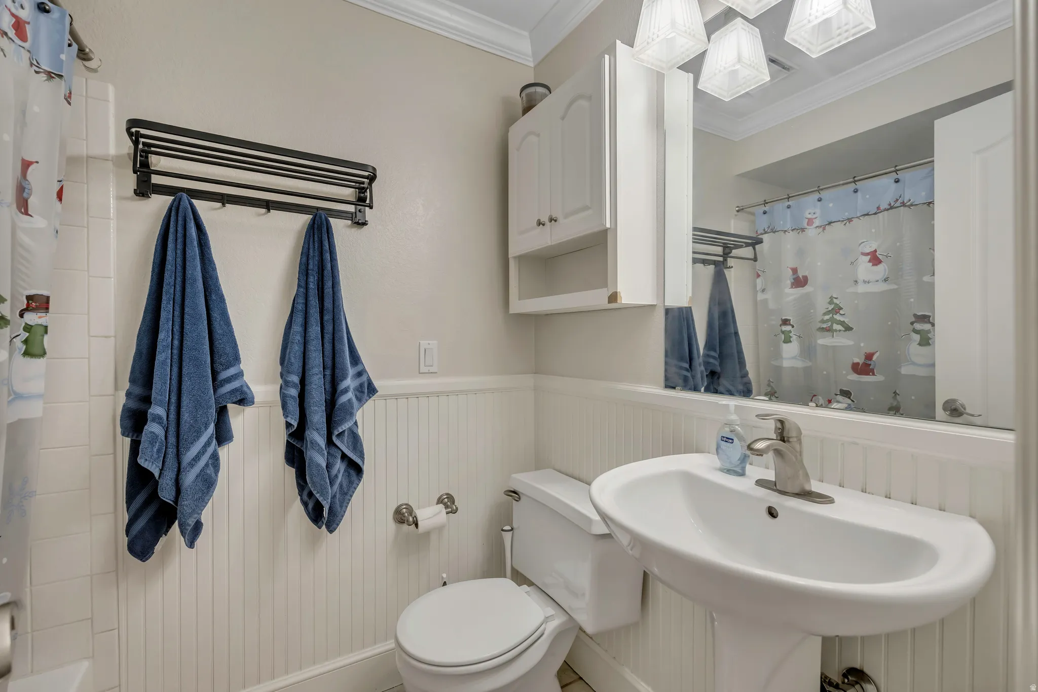 Bathroom featuring a pedestal sink with a brushed nickel faucet, a wall-mounted mirrored medicine cabinet, beadboard wainscoting, and crown molding