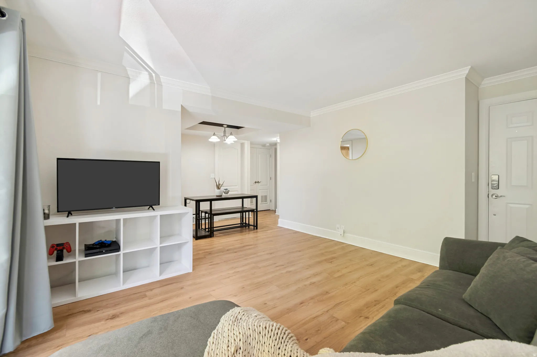 Expansive living area featuring light wood-finish flooring, crisp white walls, and crown molding