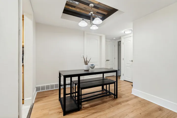Dining area featuring a wood-finish flooring, white baseboards, and a ceiling light fixture with a wood-panel accent
