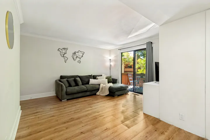 Spacious living area featuring wood-finish flooring, white baseboards, and crown molding