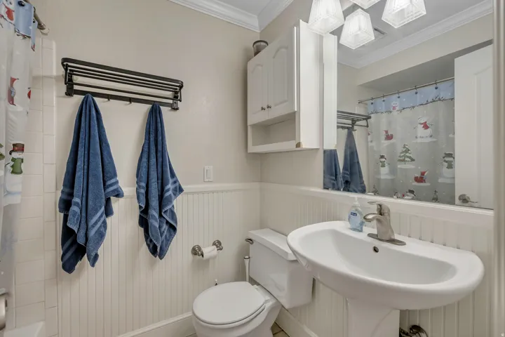 Bathroom featuring a pedestal sink with a brushed nickel faucet, a wall-mounted mirrored medicine cabinet, beadboard wainscoting, and crown molding
