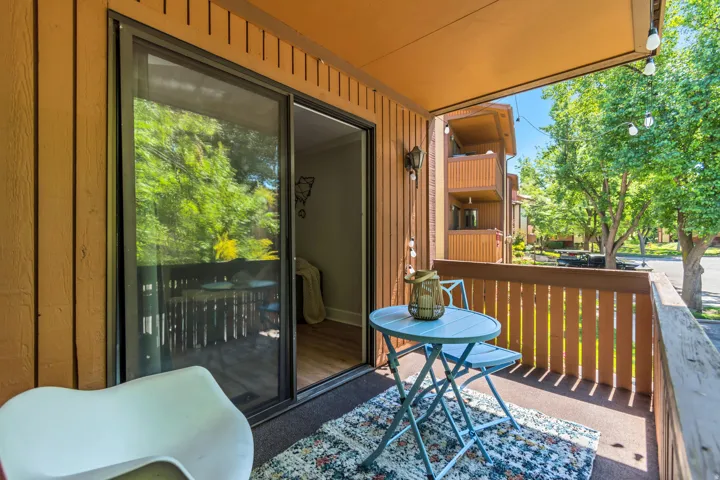 Private balcony featuring a wood fence railing, sliding glass door, and exterior lighting