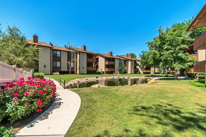 Landscaped grounds featuring a winding pathway, vibrant rose bushes, and a decorative pond