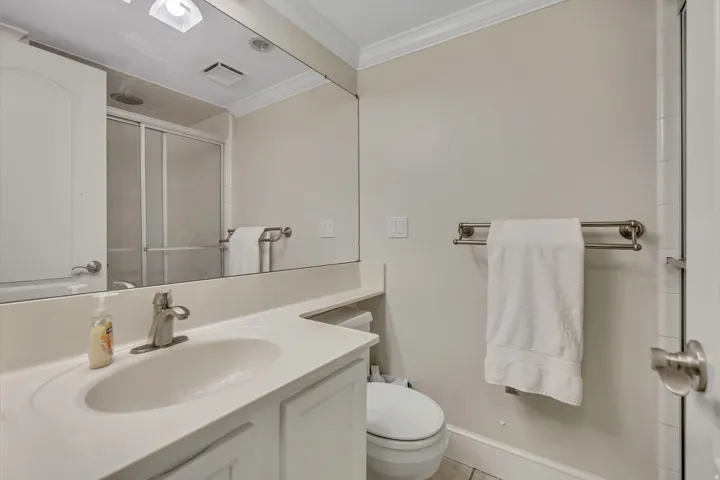 Bathroom featuring a single vanity with an integrated sink, brushed nickel faucet, large wall mirror, and a shower with sliding glass doors