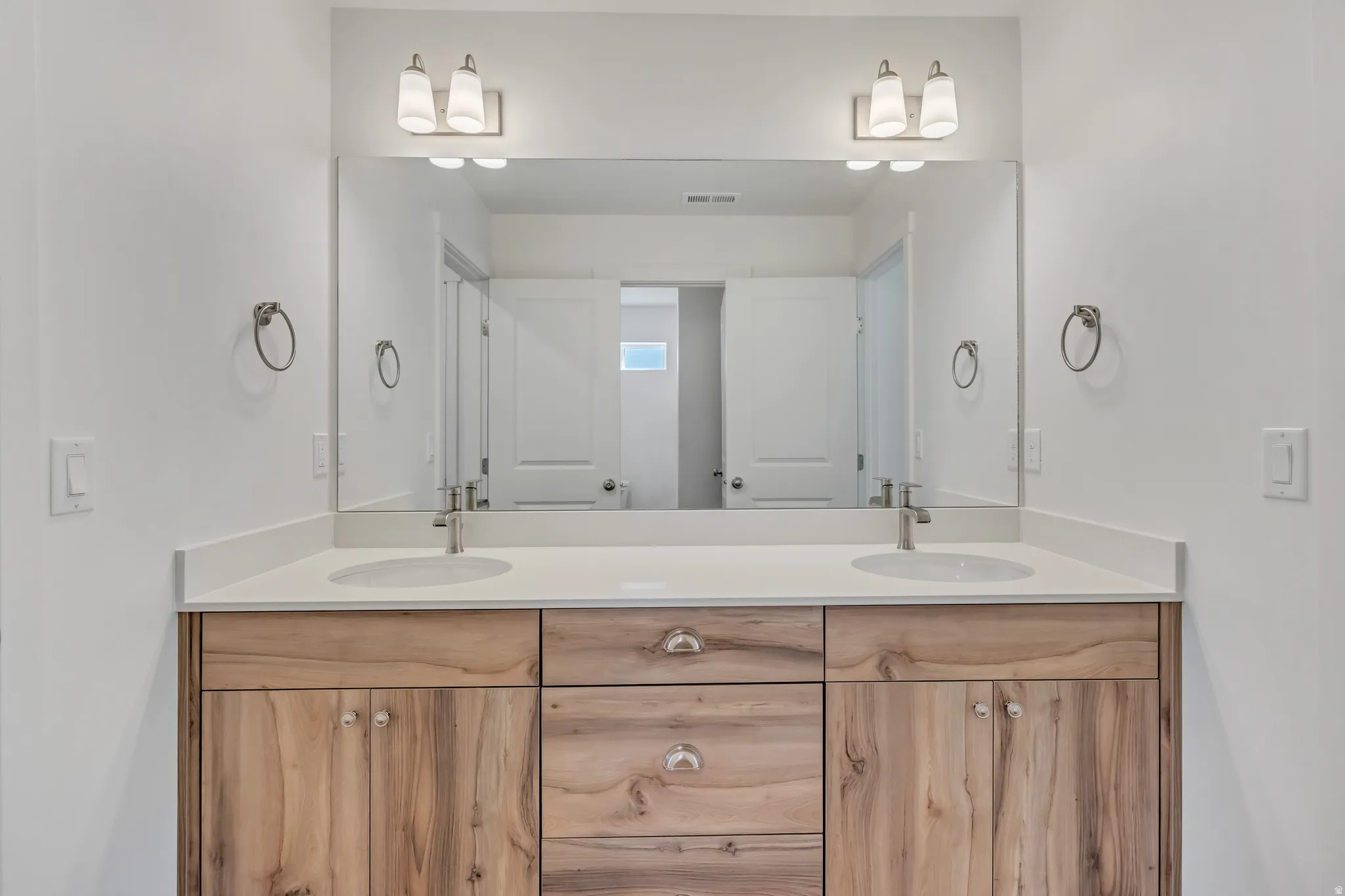 Dual vanity featuring wood-finish cabinetry, white countertops, and undermount sinks