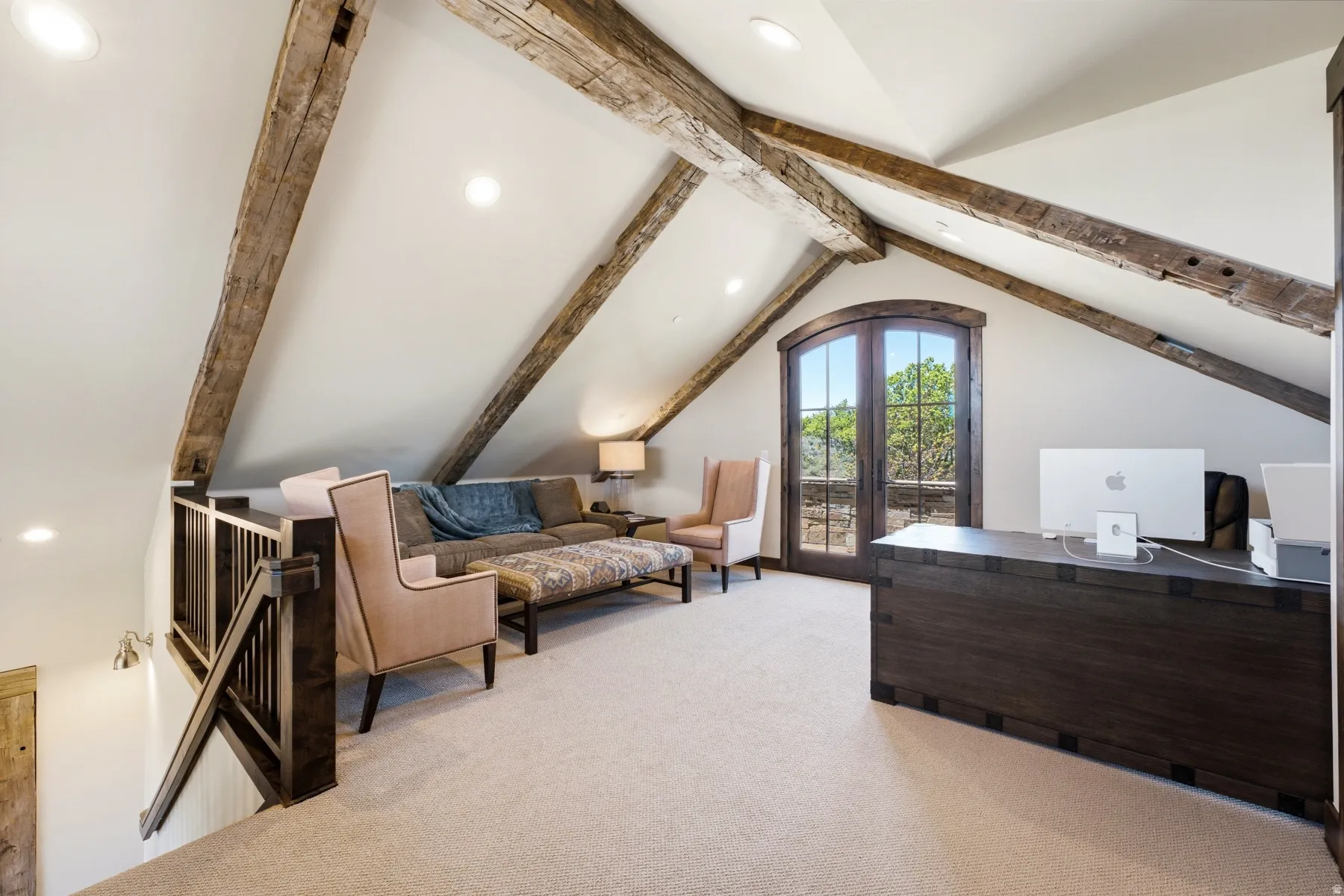 Vaulted ceiling with exposed wood beams, arched French doors, light-colored carpeting, recessed lighting, and dark wood railing