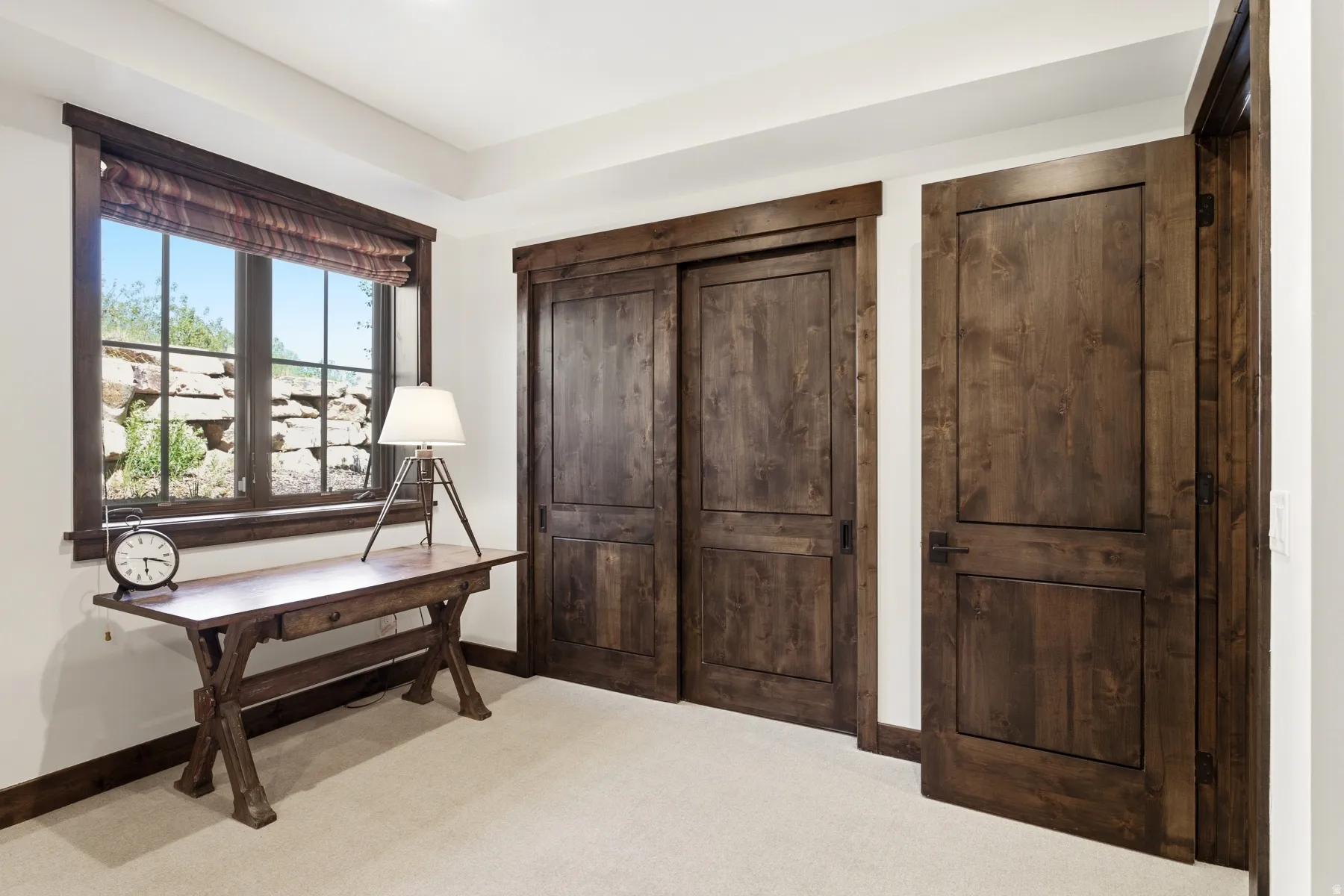 Room featuring white walls, light-colored carpeting, and dark wood-finish trim