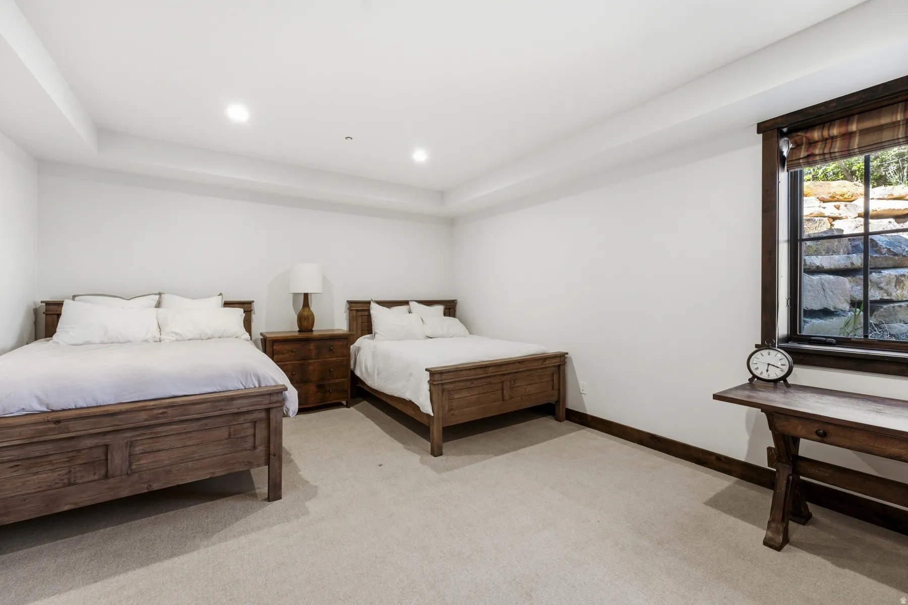 Spacious room featuring two wood-frame beds, a wood nightstand, and a built-in window with dark wood trim