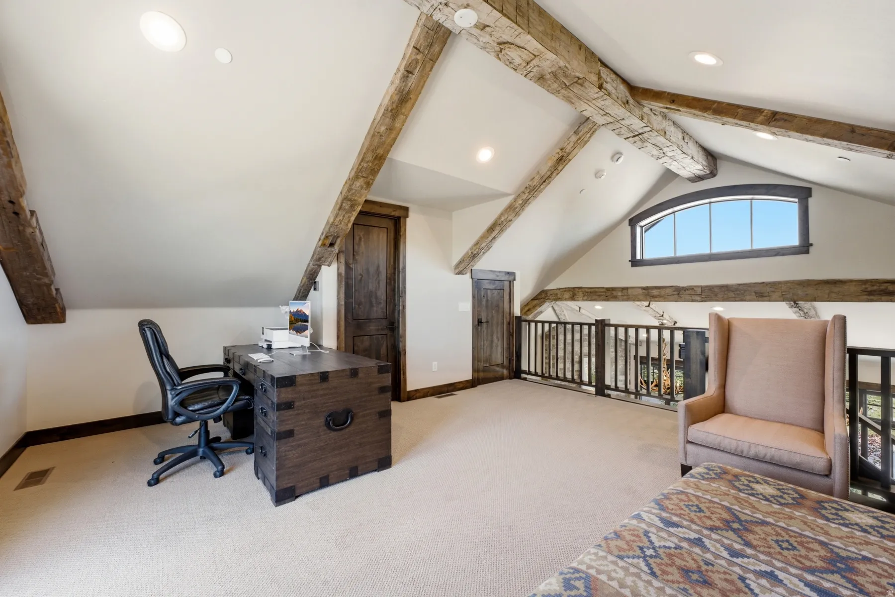 Loft space featuring exposed wood beams, vaulted ceilings with recessed lighting, an arched window, and wood-finish doors