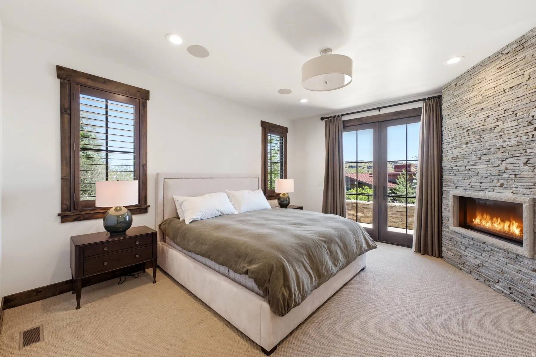 Bedroom featuring a stone-clad fireplace and direct exterior access