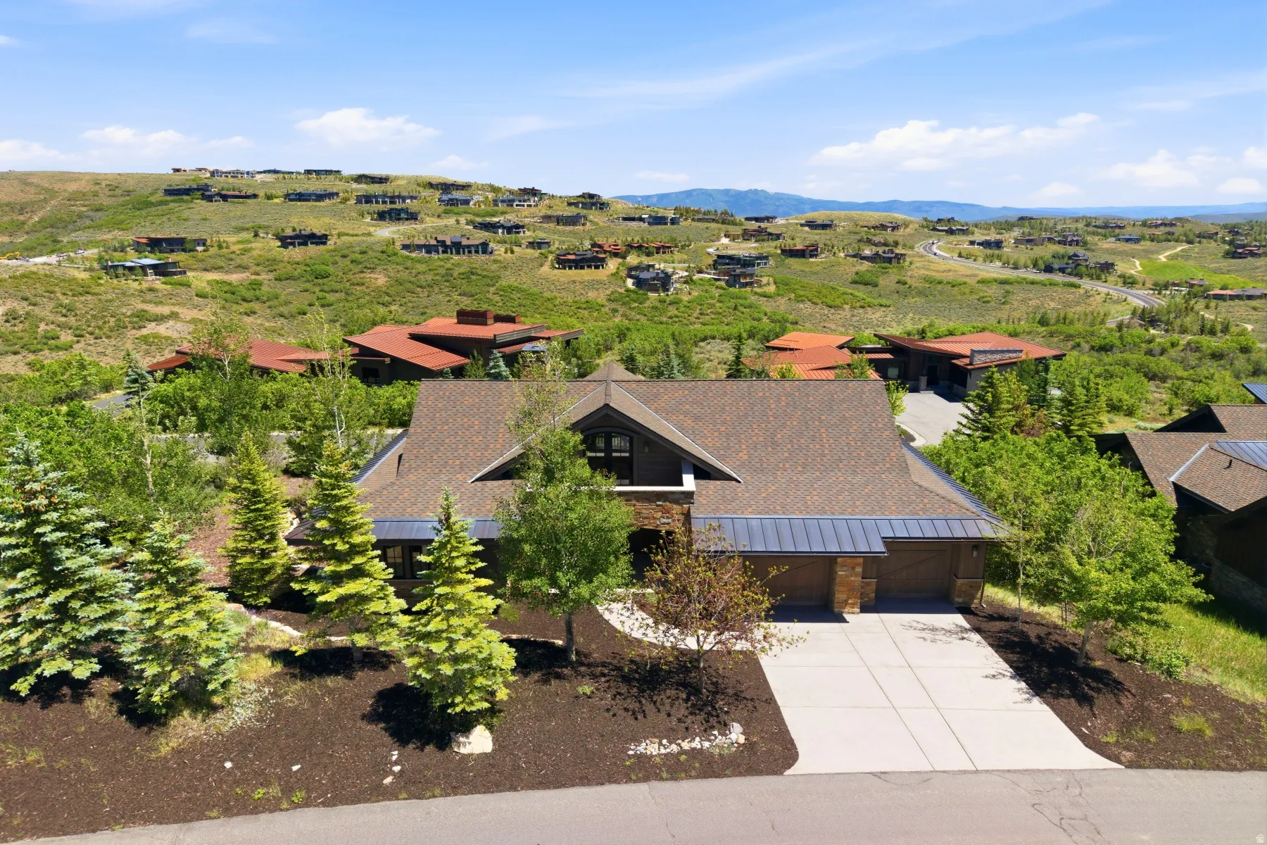 Contemporary residence featuring a multi-car garage, concrete driveway, and a stone and wood facade
