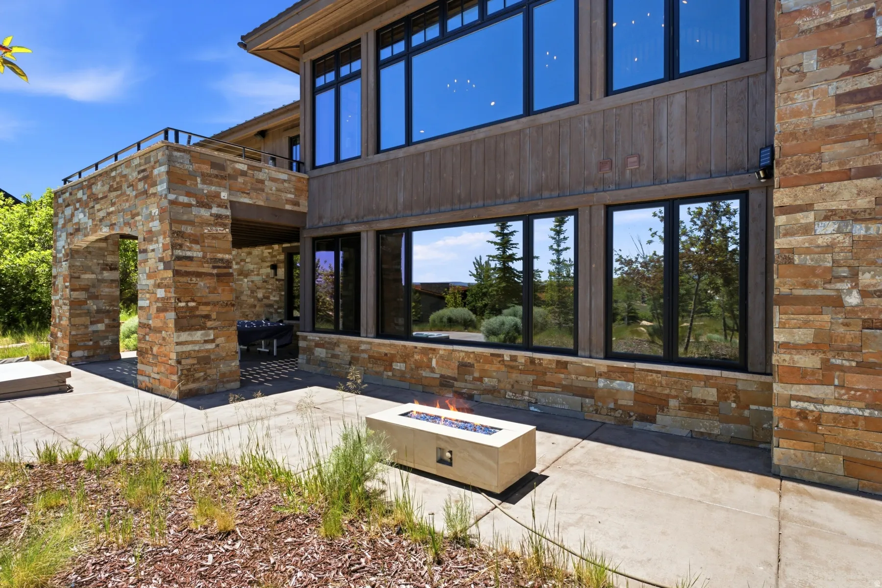 Exterior stone and wood-paneled facade with large black-framed windows