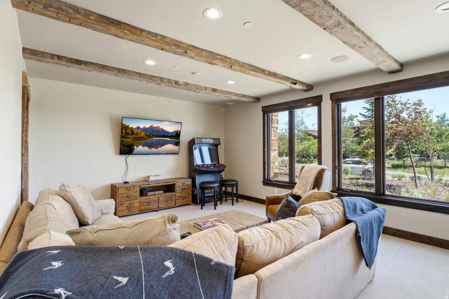 Living area featuring exposed wood ceiling beams, recessed lighting, and large windows with dark wood trim