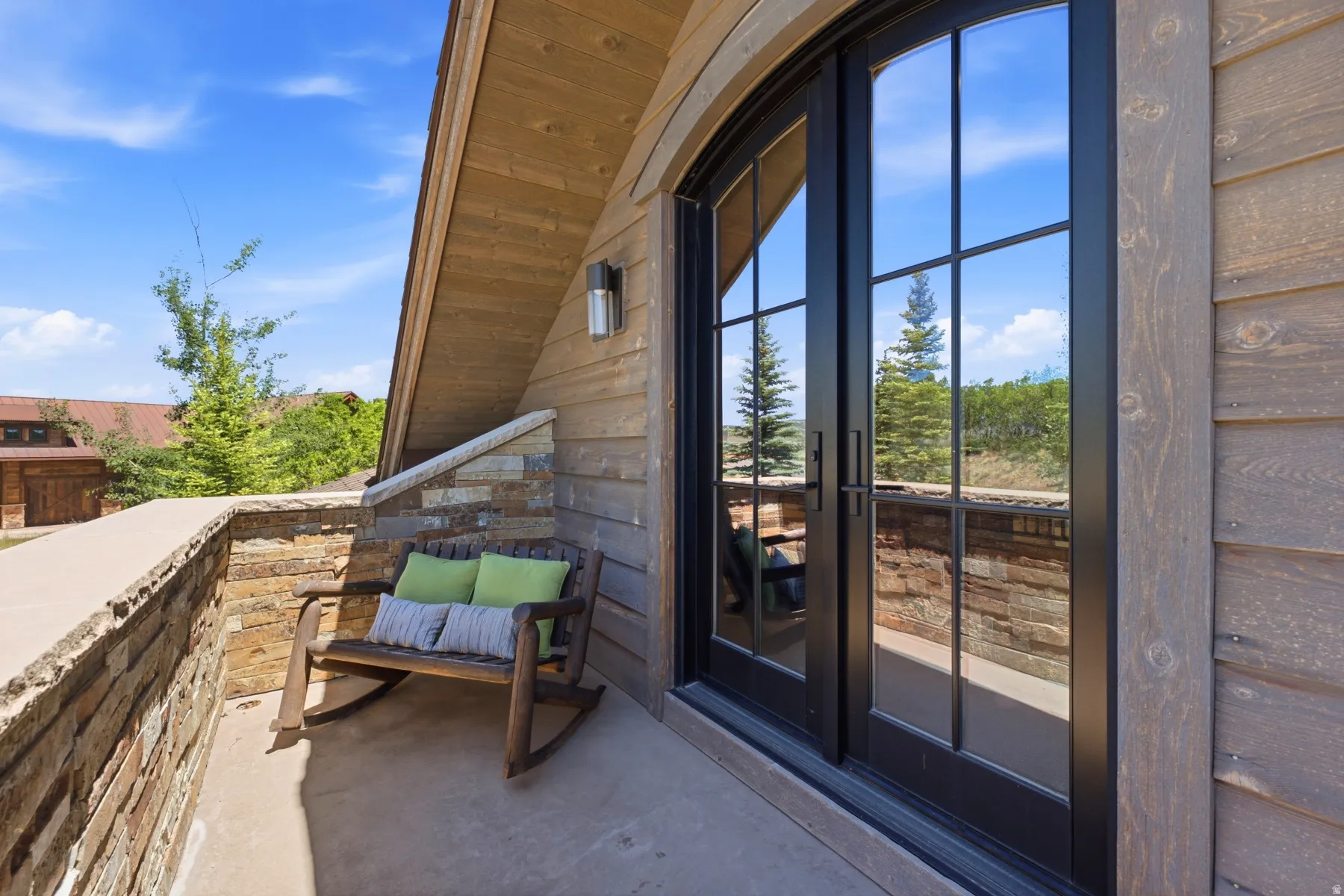 Outdoor patio featuring stone wall accents and a black-framed glass door with multiple panes