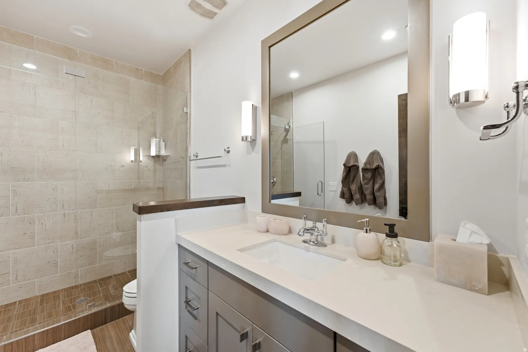 Contemporary bathroom featuring a spacious shower with light-toned wall tile and wood-finish flooring