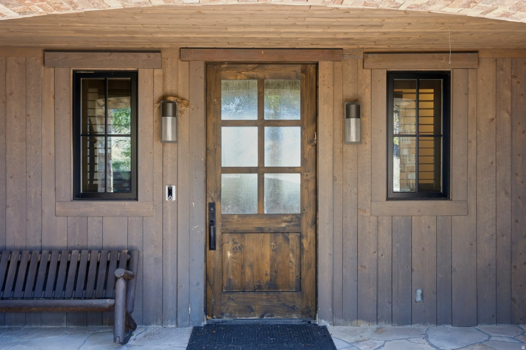 Rustic wood paneling exterior featuring a multi-pane wooden entry door with frosted glass