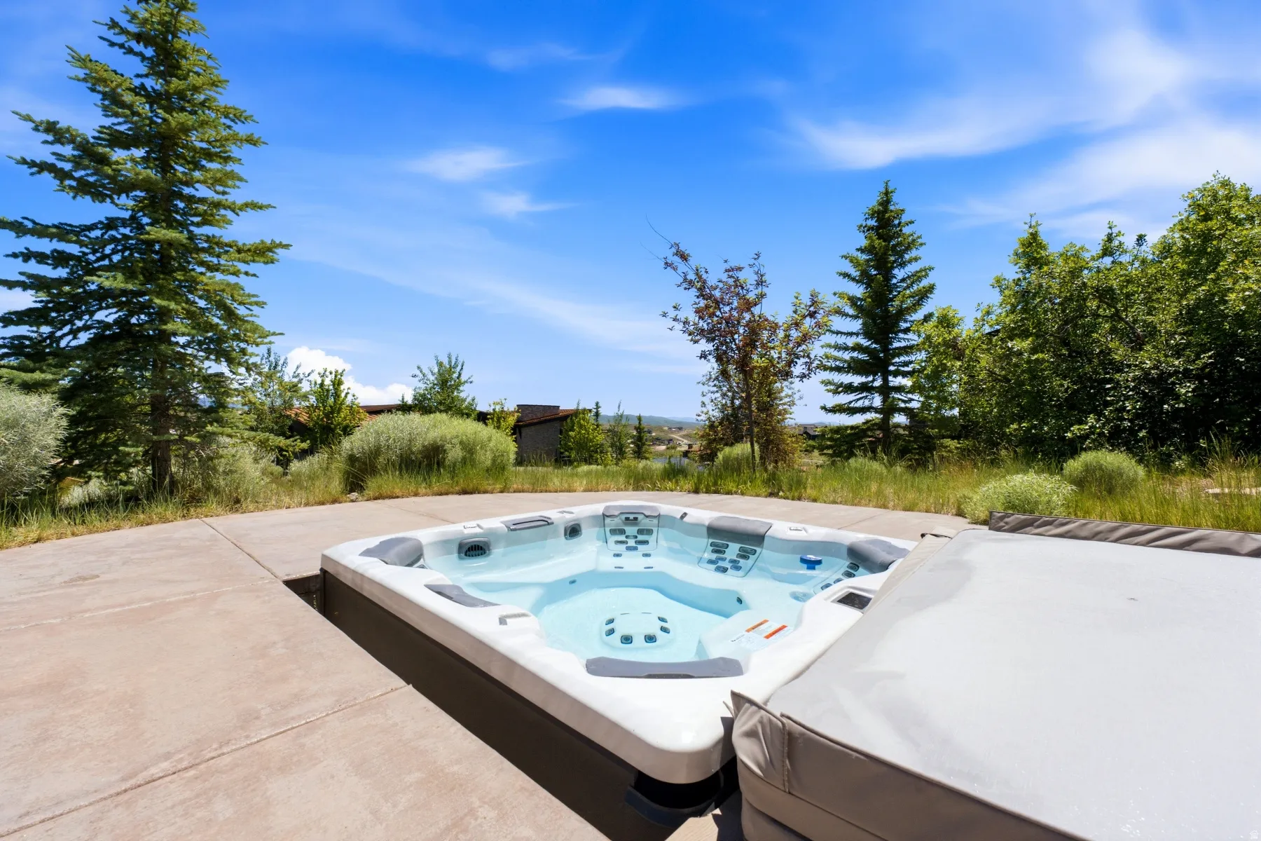 Outdoor spa with a light-toned exterior and integrated seating, set into a concrete patio