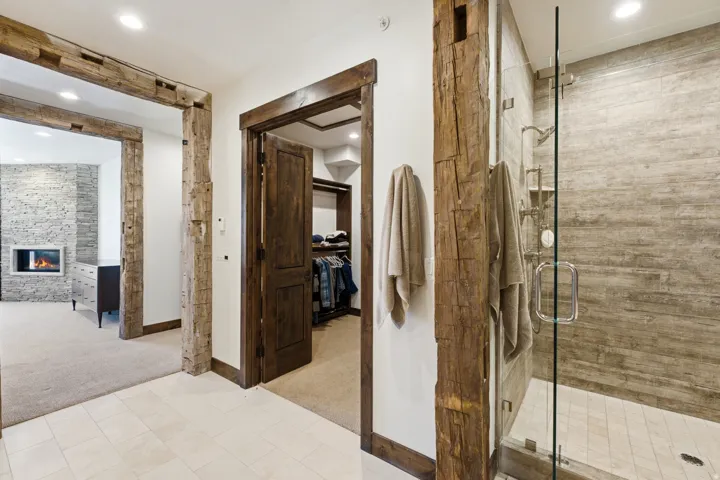 Glass-enclosed shower with subway tile surround and built-in shelving, featuring a rain shower head and separate handheld sprayer