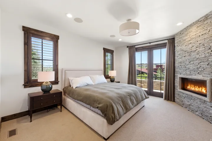 Bedroom featuring a stone-clad fireplace and direct exterior access