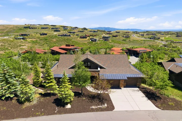Contemporary residence featuring a multi-car garage, concrete driveway, and a stone and wood facade