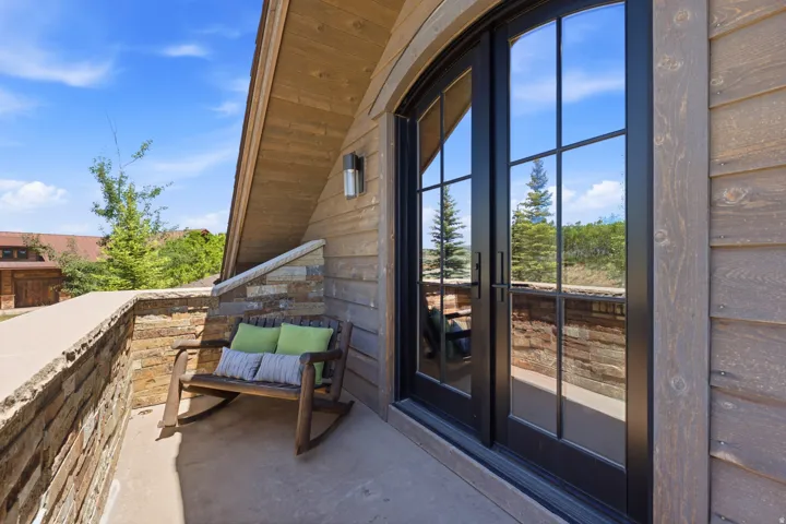 Outdoor patio featuring stone wall accents and a black-framed glass door with multiple panes