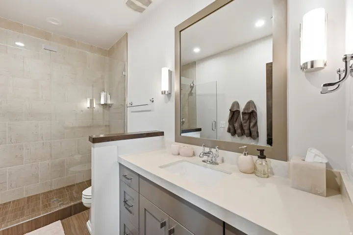 Contemporary bathroom featuring a spacious shower with light-toned wall tile and wood-finish flooring