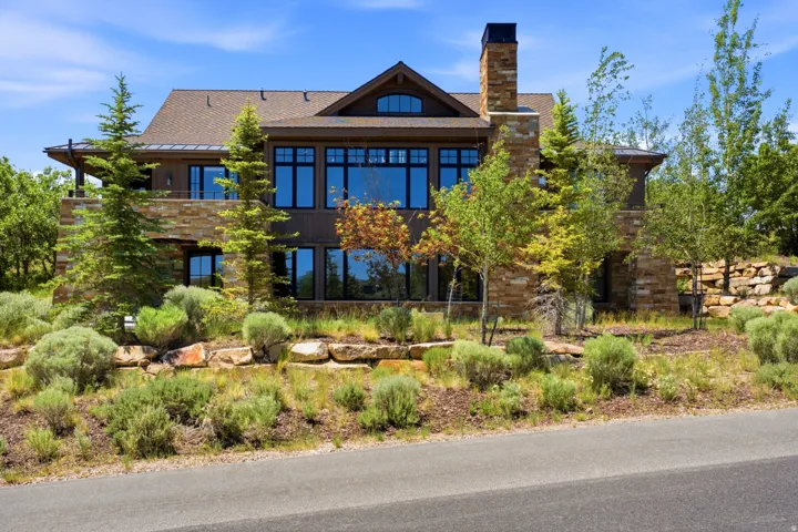 Multi-level residence featuring extensive stone accents, a prominent chimney, and a mix of dark wood siding