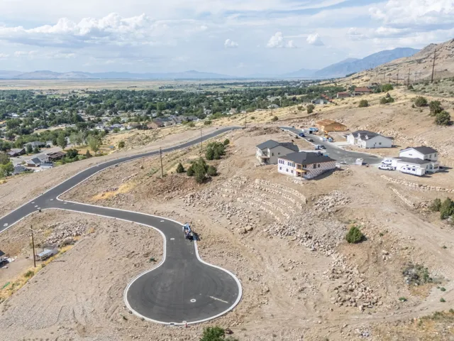 Expansive hillside development featuring newly paved roads, multiple completed residential structures, and various building sites