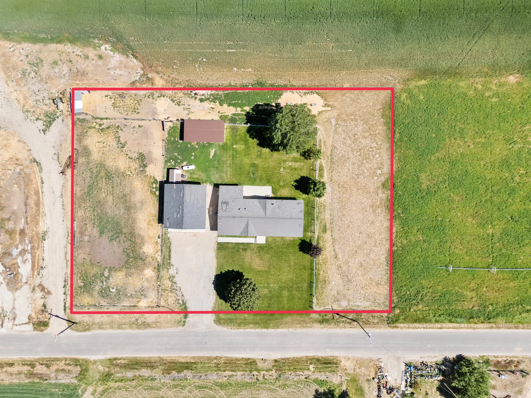 Aerial view showcasing a rectangular lot with a primary residence and detached outbuilding