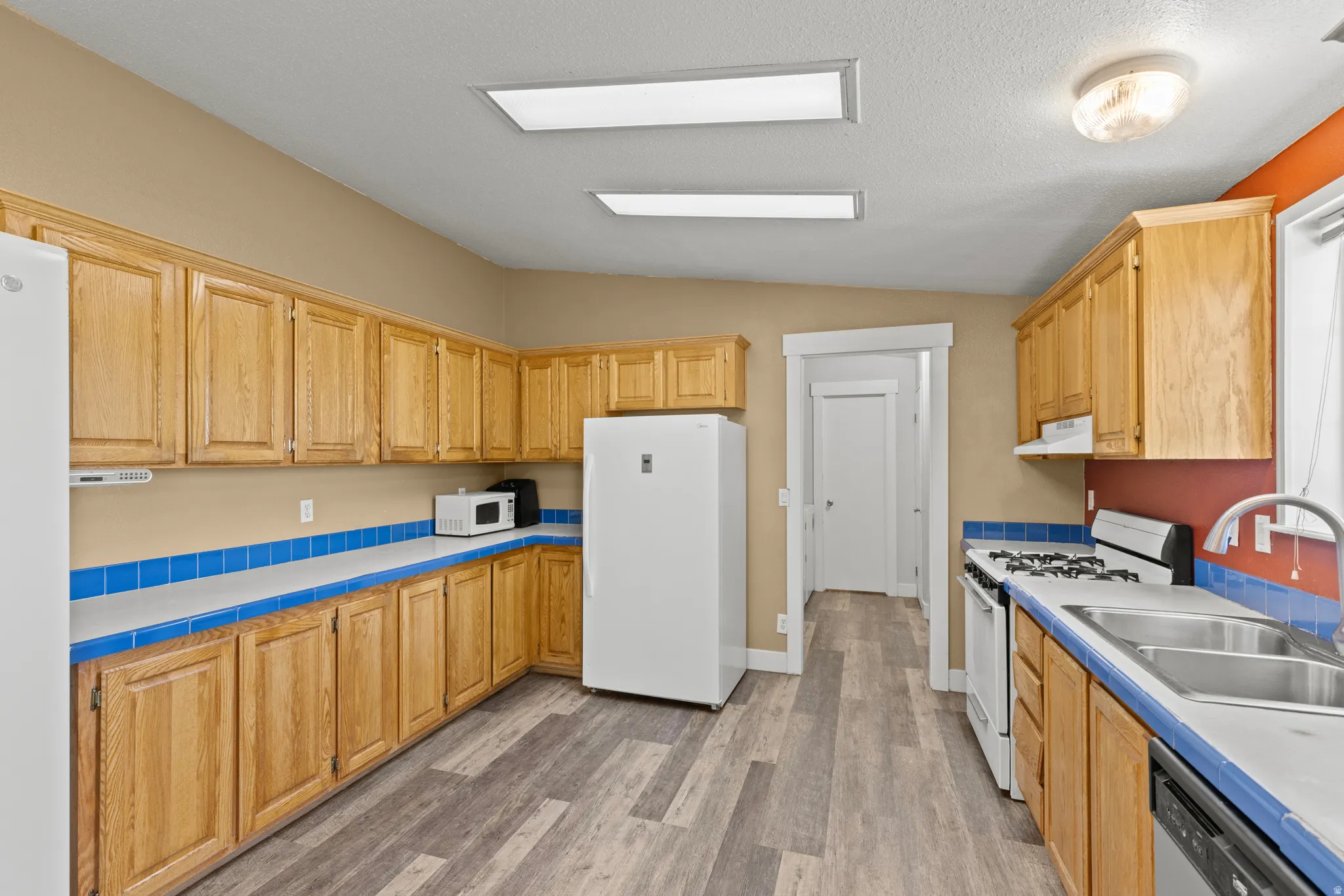 Kitchen featuring wood-finish cabinetry, tile countertops, tile backsplash, and wood-finish flooring