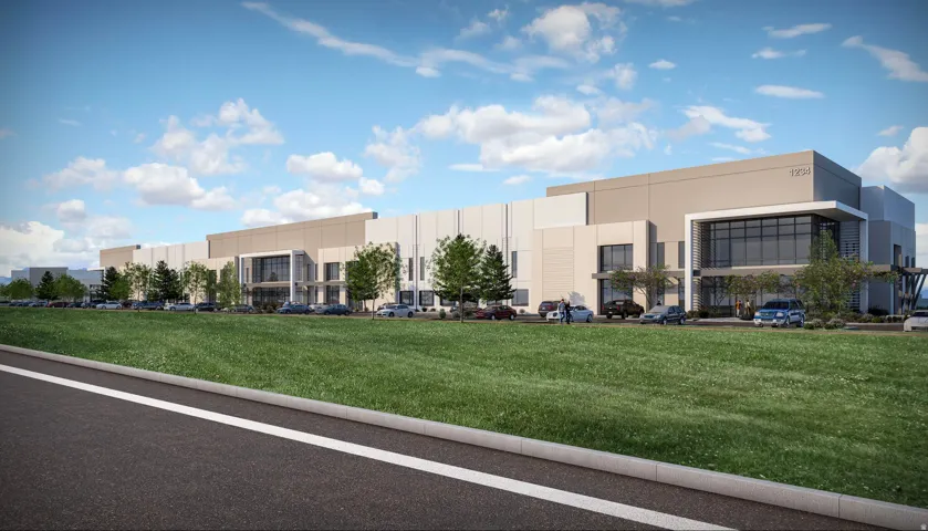 Modern industrial building featuring expansive exterior walls, a prominent glass-fronted entrance, and ample on-site parking