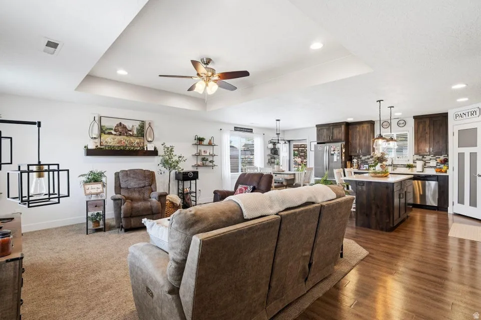 Open-concept living space featuring a tray ceiling with recessed lighting and a ceiling fan