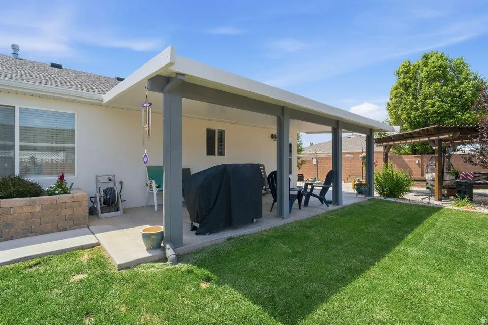 Expansive covered patio featuring a concrete surface, supported by columns, and offering direct access to the grassy yard