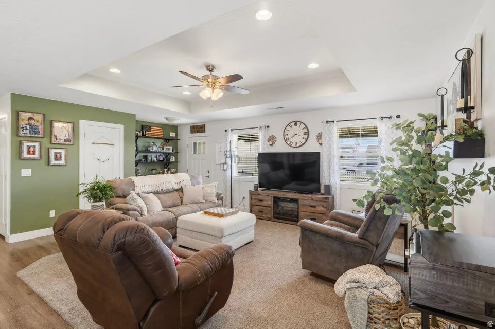 Spacious living area featuring a tray ceiling with recessed lighting and a ceiling fan
