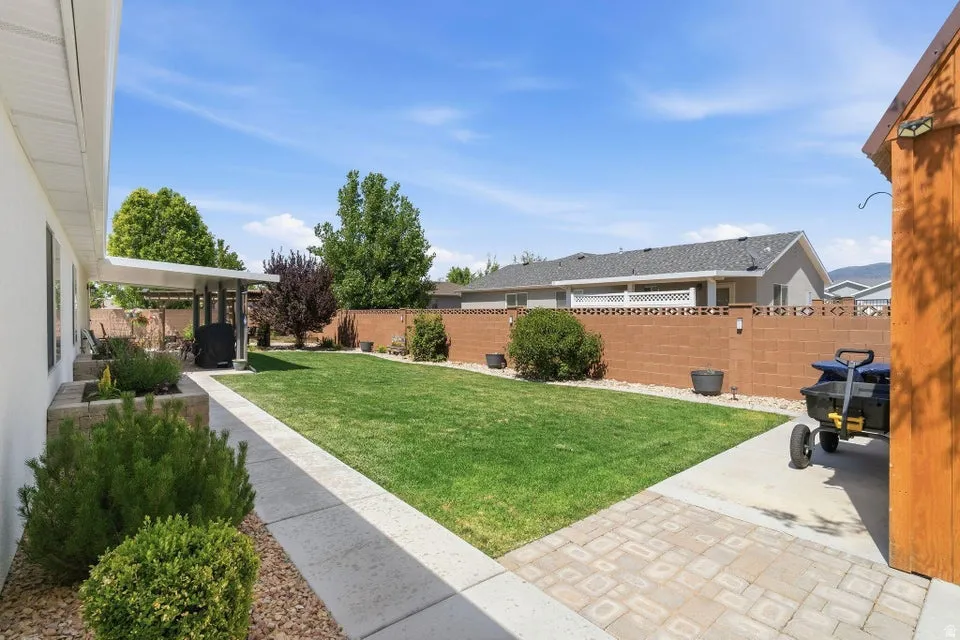 Expansive backyard featuring a manicured lawn, concrete patio, and a covered pergola