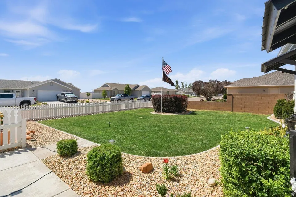 Manicured front lawn with a white picket fence, concrete walkway, and decorative rock landscaping